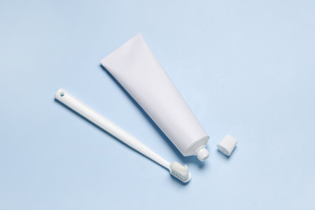 Plastic toothbrush and paste on light background, flat lay
