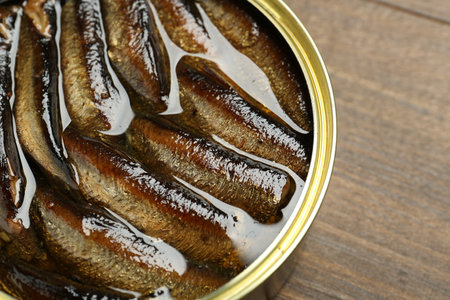 Sprats in tin can on wooden table, closeup. Space for textの写真素材