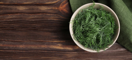 Fresh dill in bowl on wooden table, top view. Banner design with space for textの写真素材