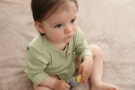 Cute baby girl with nibbler on beige blanketの写真素材