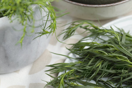 Plate and mortar with fresh tarragon leaves on table, closeupの写真素材