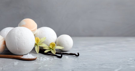 Many different bath bombs with vanilla sticks and flowers on light gray table. Space for textの写真素材