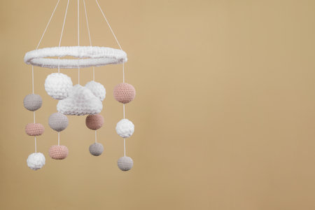 Cute baby crib mobile on beige background. Space for text