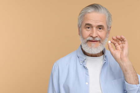 Senior man with pill on beige background. Space for textの写真素材
