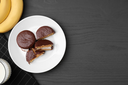 Tasty sweet choco pies, bananas and glass of milk on gray wooden table, flat lay. Space for textの写真素材