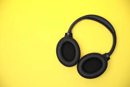 Modern wireless headphones on yellow background, top view. Space for textの写真素材