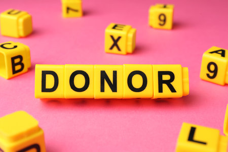 Word Donor made of yellow cubes on pink background, closeupの写真素材