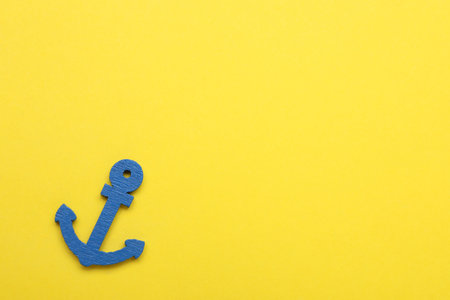 Anchor figure on yellow background, top view. Space for textの写真素材
