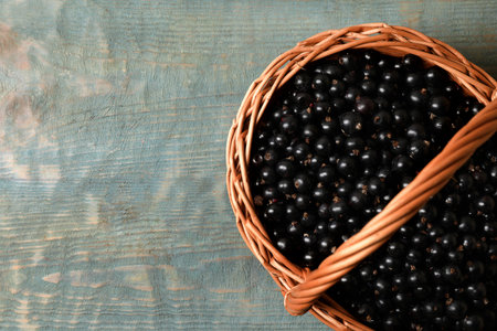 Ripe blackcurrants in wicker basket on wooden rustic table, top view. Space for textの写真素材