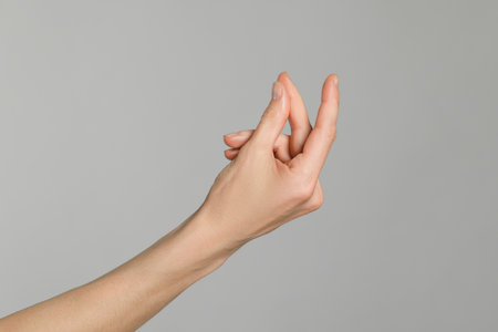 Woman snapping her fingers on light gray background, closeup. Bad habitの写真素材