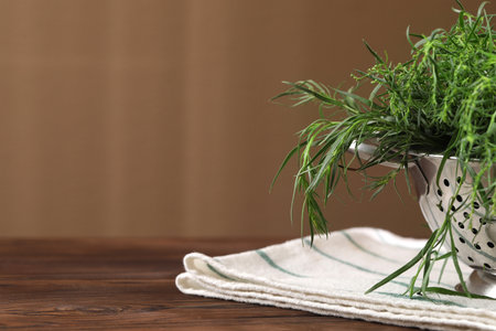 Colander with fresh tarragon leaves on wooden table, closeup. Space for textの写真素材