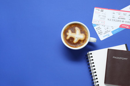Flat lay composition with passport, cup of coffee and tickets on blue table, space for text....