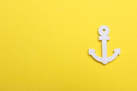 Anchor figure on yellow background, top view. Space for textの写真素材