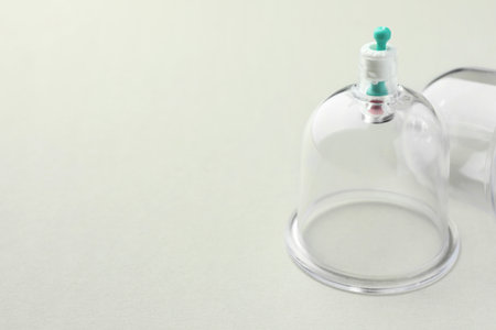 Plastic cups on light gray background, closeup with space for text. Cupping therapy