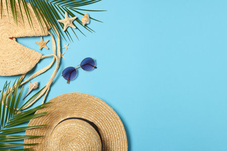 Flat lay composition with bag, palm leaves and other beach accessories on light blue background. Space for textの写真素材