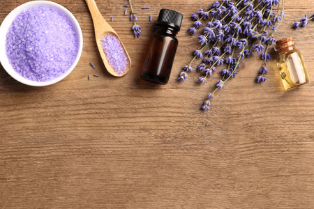 Bowl of sea salt, essential oil and lavender flowers on wooden table, flat lay. Space for textの写真素材