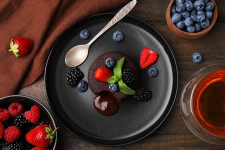 Plate with delicious chocolate fondant, berries and mint on wooden table, flat layの写真素材