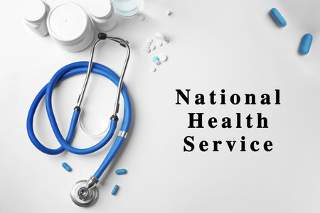 National health service (NHS). Stethoscope, pills and text on white background, top viewの写真素材