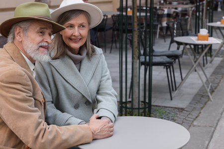Portrait of affectionate senior couple sitting in outdoor cafe, space for textの写真素材
