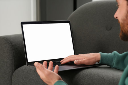Man using laptop on gray couch, closeupの写真素材