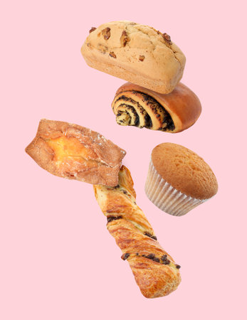 Aromatic fresh pastries falling on pink backgroundの写真素材