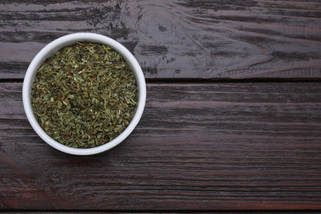 Dry tarragon in bowl on wooden table, top view. Space for textの写真素材