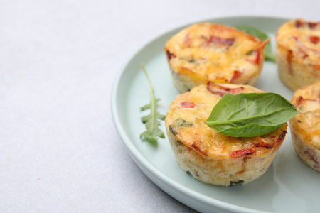 Freshly baked bacon and egg muffins with cheese on light gray table, closeup. Space for textの写真素材