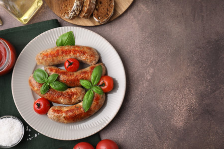 Flat lay composition with tasty homemade sausages, basil leaves and tomatoes on brown textured table. Space for textの写真素材