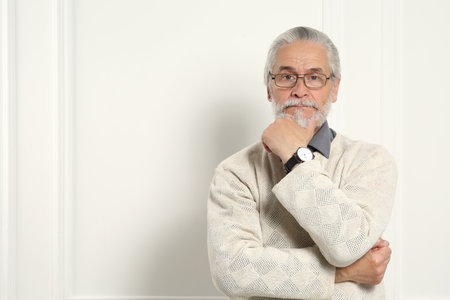 Portrait of handsome senior man in eyeglasses near white wall. Space for textの写真素材