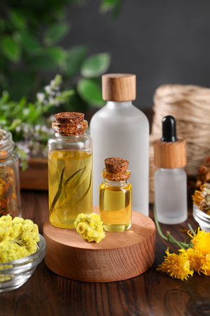 Bottles of essential oils and different herbs on wooden tableの写真素材
