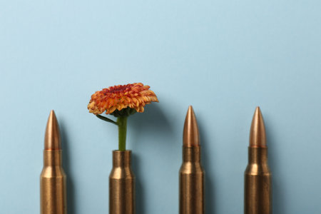 Bullets and cartridge case with beautiful flower on light blue background, flat layの写真素材