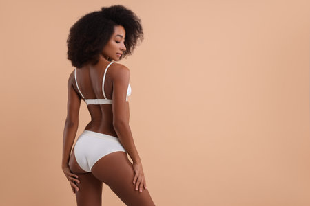 Beautiful woman in stylish bikini on beige background, space for textの写真素材