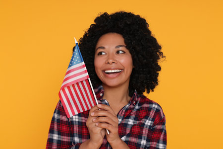 4th of July - Independence Day of USA. Happy woman with American flag on yellow backgroundの写真素材