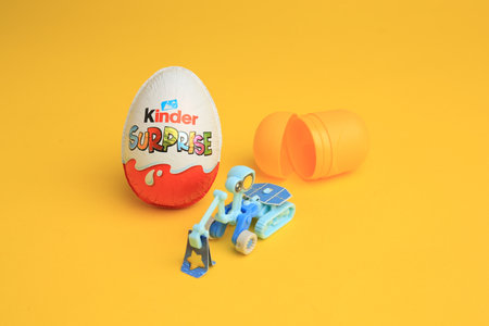 Sveti Vlas, Bulgaria - July 3, 2023: Kinder Surprise Egg, plastic capsule and toy on yellow...