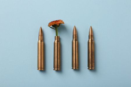 Bullets and cartridge case with beautiful flower on light blue background, flat layの写真素材