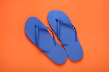 Stylish blue flip flops on orange background, top viewの写真素材