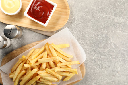 Delicious French fries served with sauces on light gray table, flat lay. Space for textの写真素材