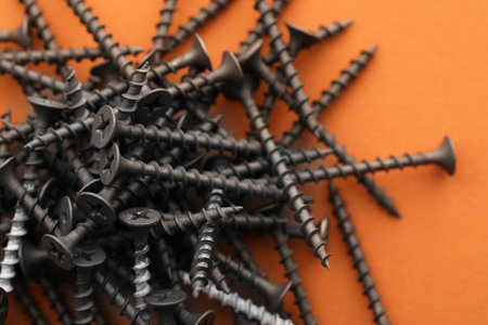 Many metal screws on orange background, closeupの写真素材