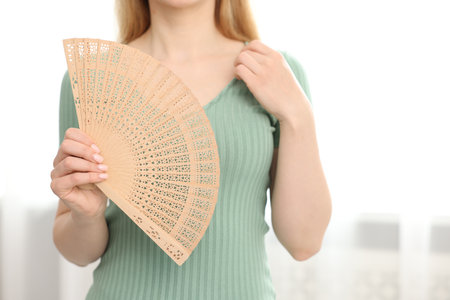 Woman with hand fan at home, closeupの写真素材