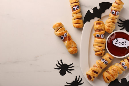 Flat lay composition with tasty sausage mummies for Halloween party on white marble table. Space for textの写真素材