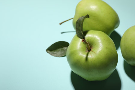 Fresh green apples on light blue background, closeup. Space for text