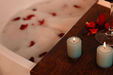 Wooden board with burning candles on bath tub, closeupの写真素材