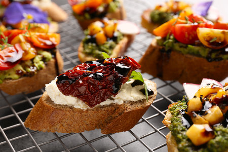 Delicious bruschettas with different toppings and balsamic vinegar on cooling rack, closeupの写真素材