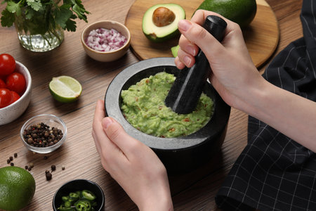 Woman preparing delicious guacamole at wooden table, closeupの写真素材