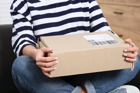 Woman with parcel at home, closeup. Online storeの写真素材