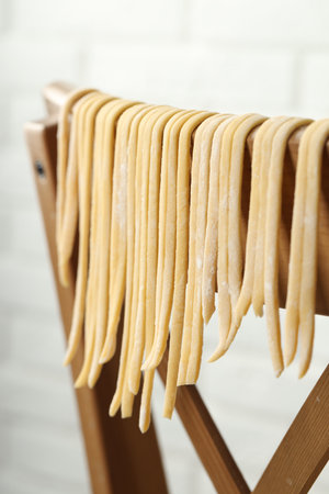 Homemade pasta drying on chair against white background, closeupの写真素材