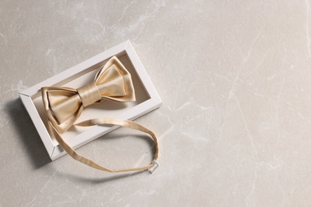 Stylish pale yellow bow tie on beige marble background, top viewの写真素材