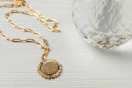 Necklace and bottle of perfume on white wooden table, closeupの写真素材
