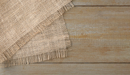 Piece of burlap fabric on wooden table, top view. Space for textの写真素材