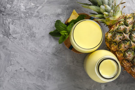 Tasty pineapple smoothie, mint and fruit on gray textured table, flat lay. Space for textの写真素材